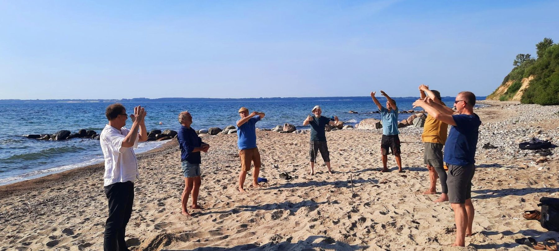 Eine Männergruppe macht Übungen am Ostseestrand